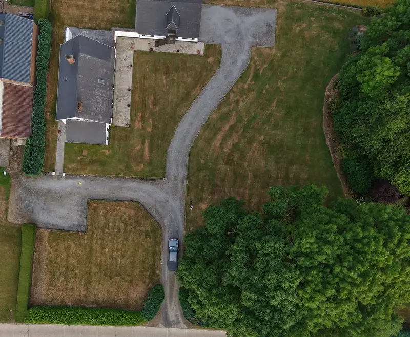 Vue aérienne avant travaux : ancienne allée en gravier gris menant à la maison