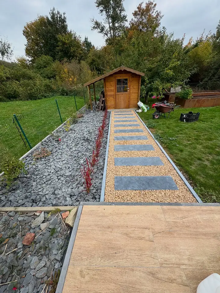 Après travaux : allée en pas japonais en pierre bleue menant à l'abri de jardin, bordée de plantations