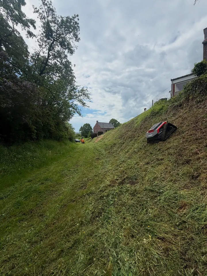 Débroussailleuse radiocommandée sur un talus en forte pente, herbe fraîchement coupée