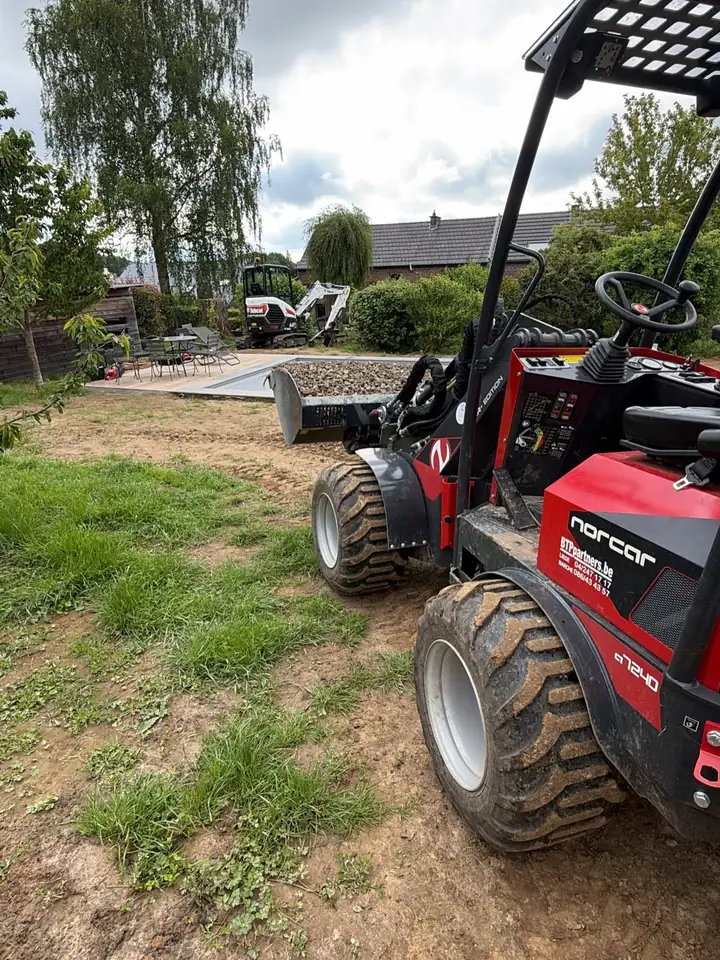 Chargeuse compacte Norcar 7240 rouge sur un chantier de jardin