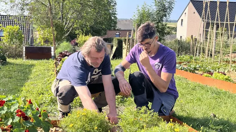 Nour et Benoît Blairvacq accroupis au bord d'un bac de culture fleuri de capucines et de tagètes