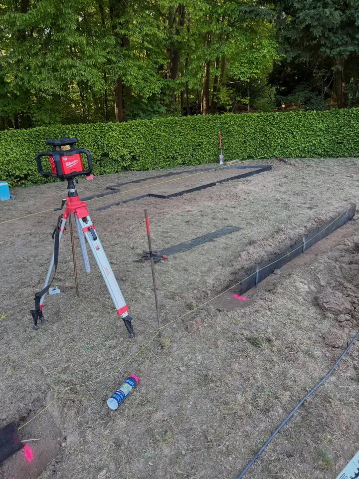 Laser de chantier sur trépied et repères d'implantation sur un terrain préparé